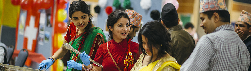 A group of students in multicultural dress have a chat.