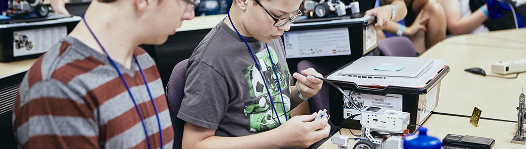 Two students study some mechanical parts at a table.