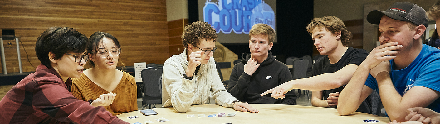 A group of individuals gather around a table to test an educational board game....