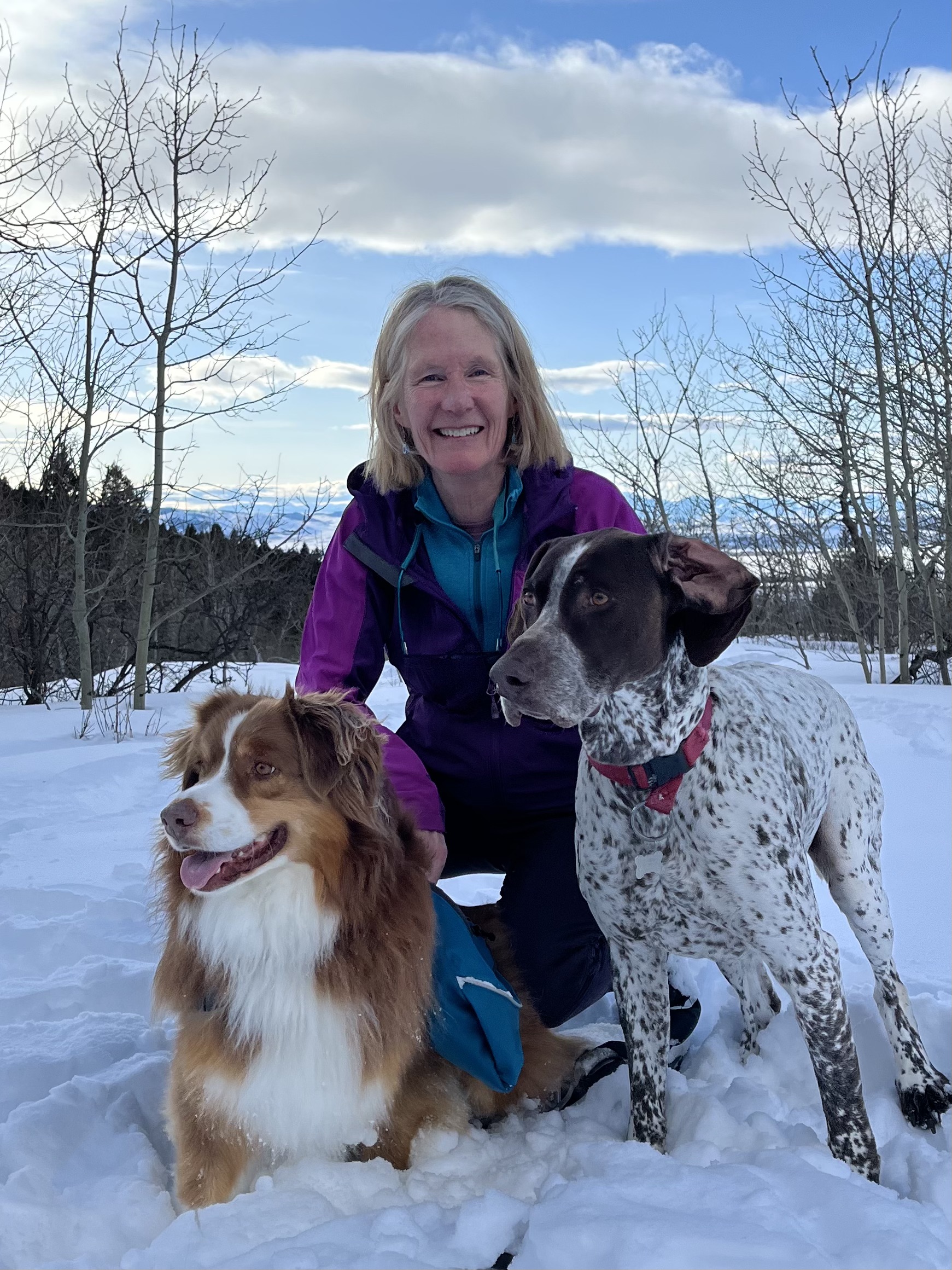 janet A woman kneeling down with two medium sized dogs smiling at the camera