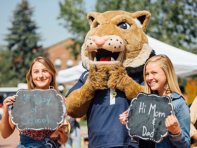 Two students stand with Champ on campus.