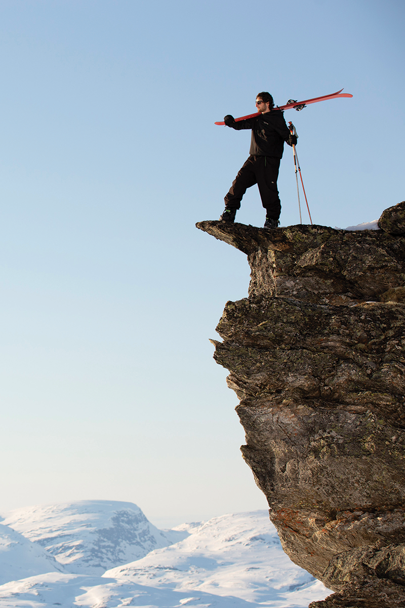 A person holding skis standing on a cliffside