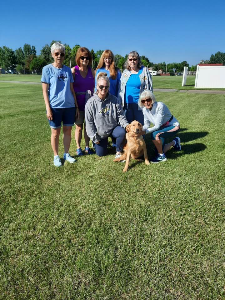 Strong Women take a break to play with River, the fair Mascot Golden Retriever