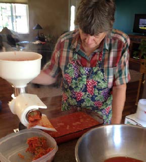 A woman stands in her kitchen making a product meant to be stored in jars.