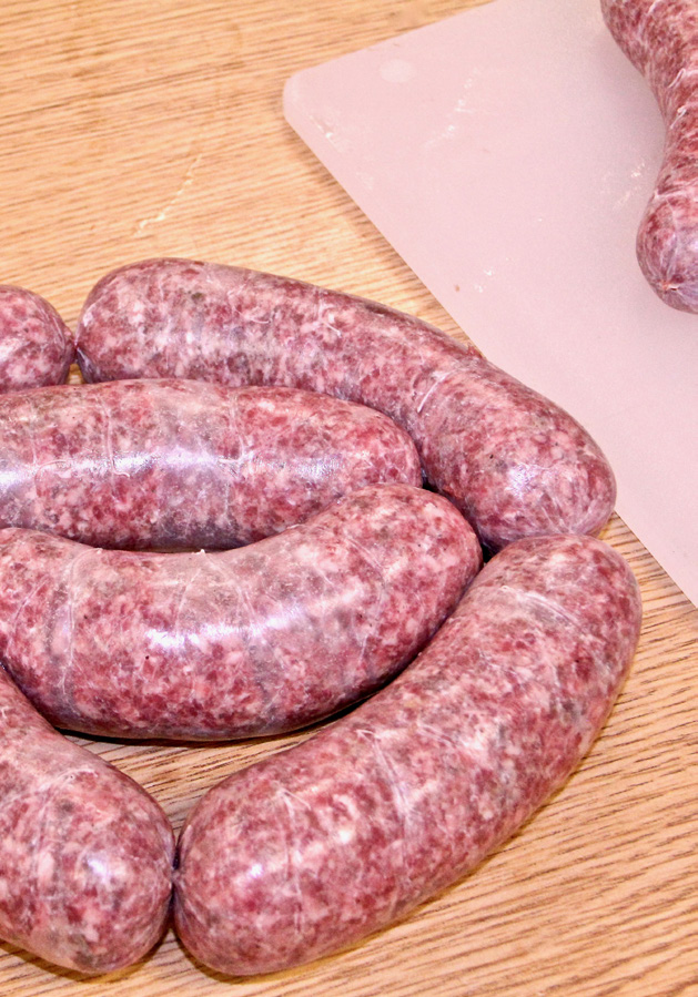 Freshly cased sauage lies in rounds on a table.