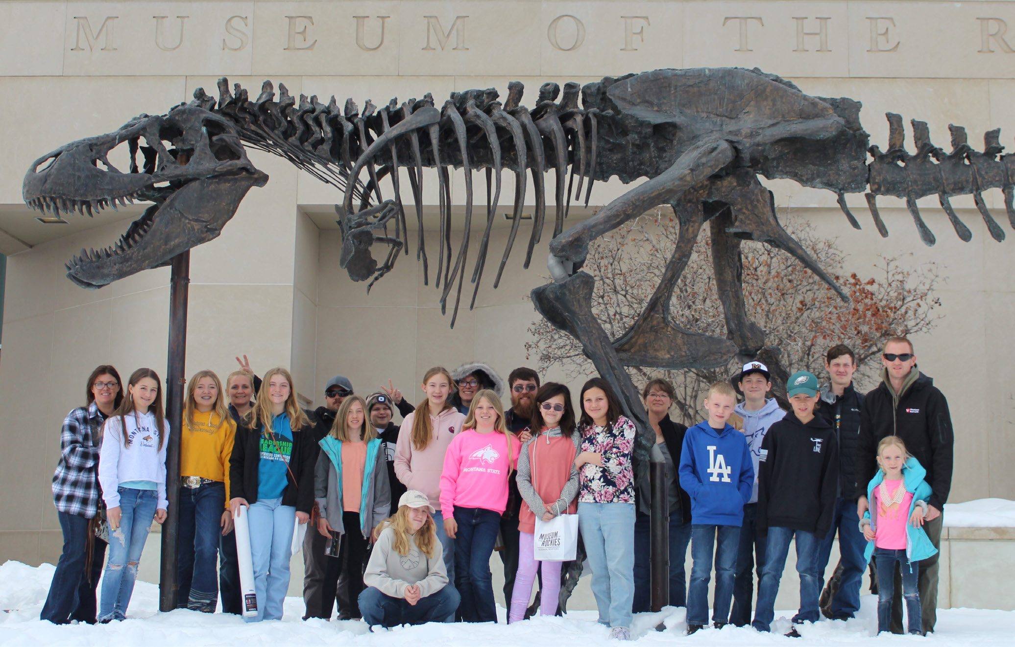 Group of youth stand in front of a Museum of the Rockies life size dinosuar replica.