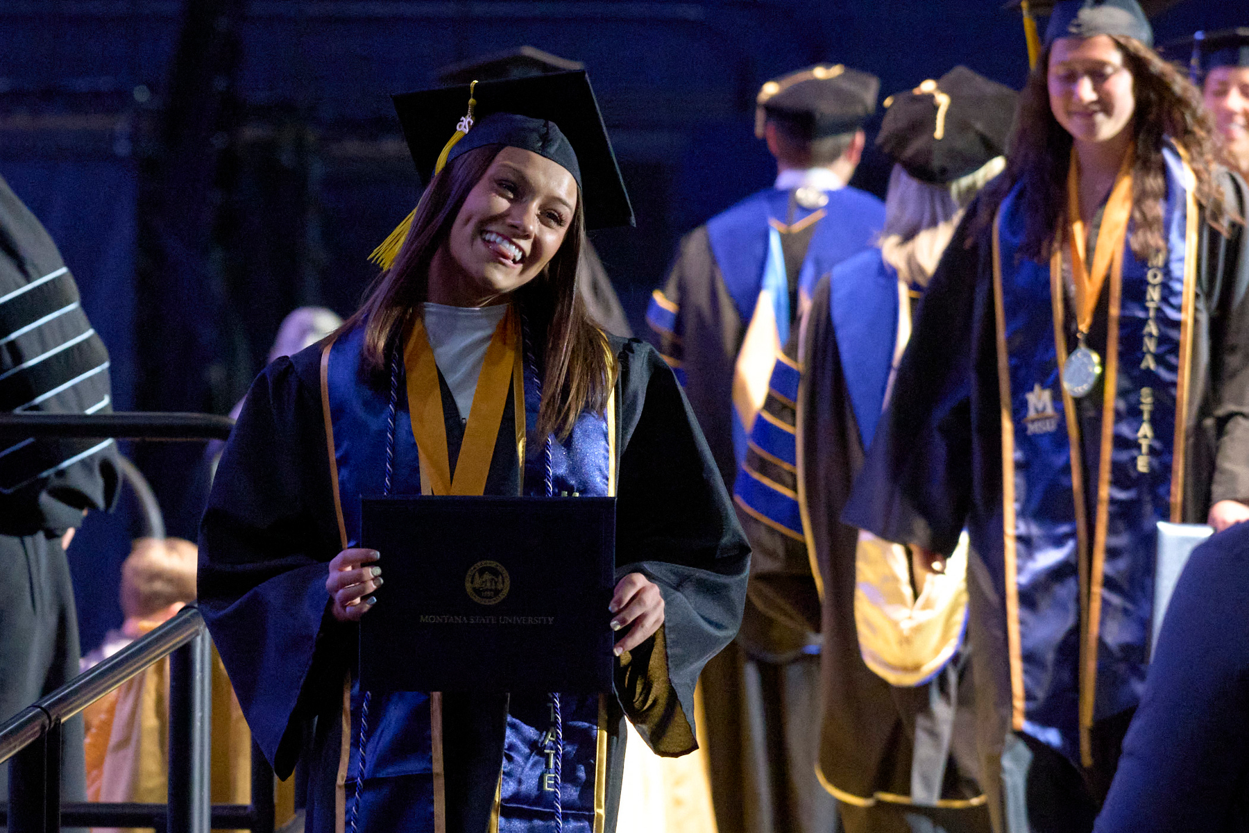 Student walking across the stage at commencement wearing a first-generation honor cord