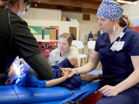 A child gets a dental screening from a dentist and dental assistant