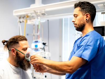 A respiratory therapist attaches a breathing device to a patient's face.
