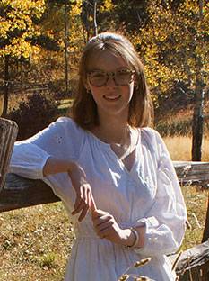 photographic portrait of Nela Ward in front of deciduous trees with gold-colored leaves