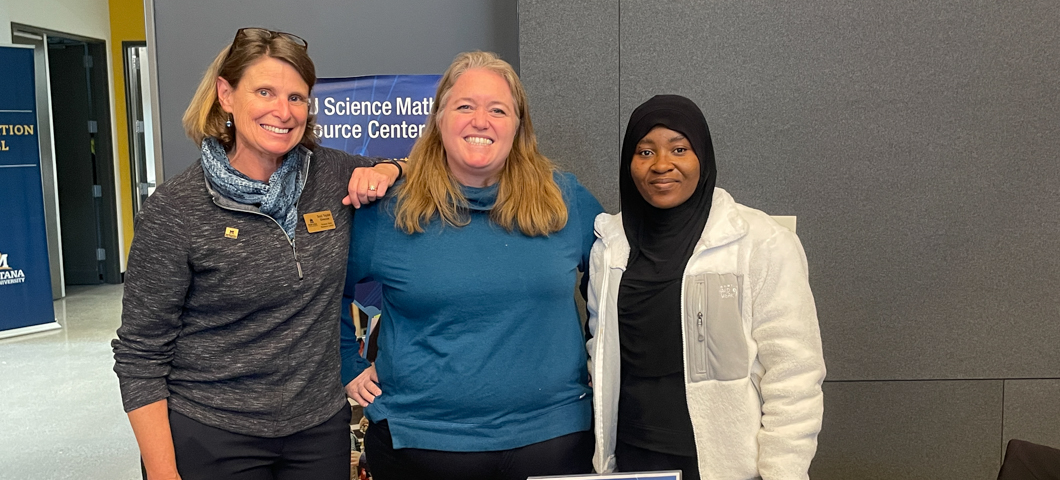 Three SMRC staff behind a table at an event