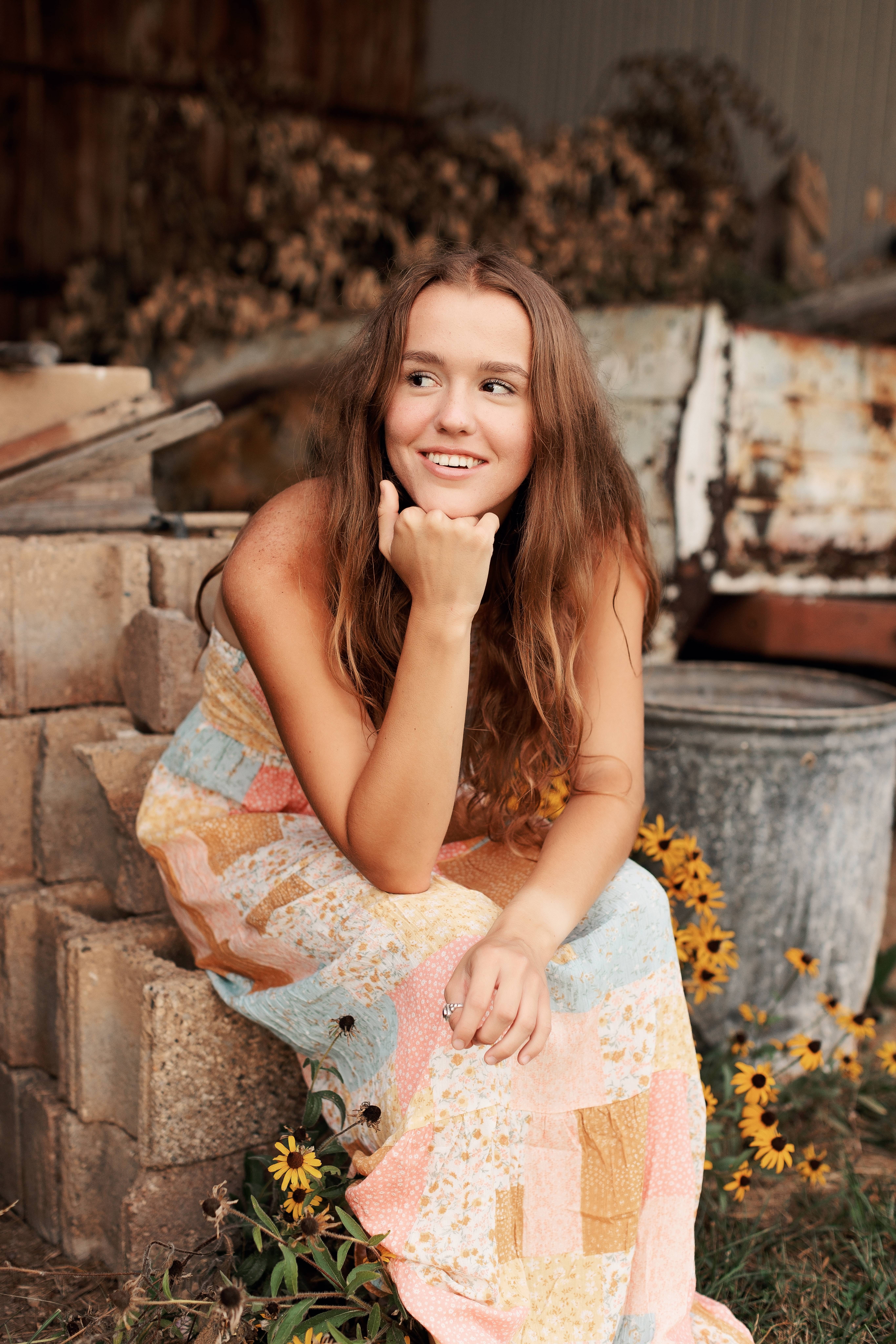 Female student wearing a long dress while sitting on a park bench